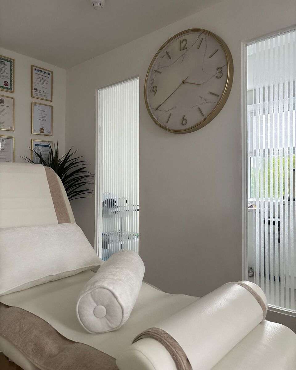 The reflexology couch made up with rolled bolster cushions, beneath the marble faced gold wall clock in the clinic